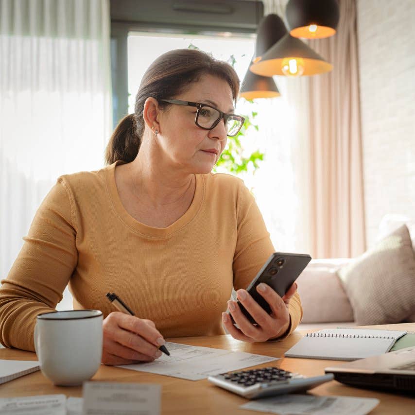 Woman using mobile phone and laptop working from home. Home finances. Calculating budget. Preparing taxes